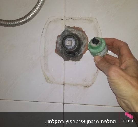 יד מחזיקה חלק אינסטלציה ליד קיר עם צינור מתכת